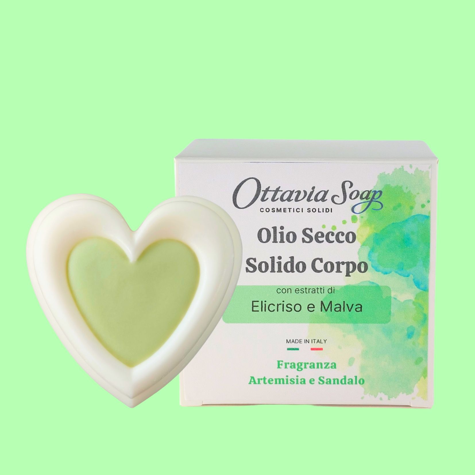 Olio Secco Solido con estratti di Elicriso e Malva In primo piano un panetto bianco a forma di cuore ed in secondo piano la confezione con l’etichetta descrittiva