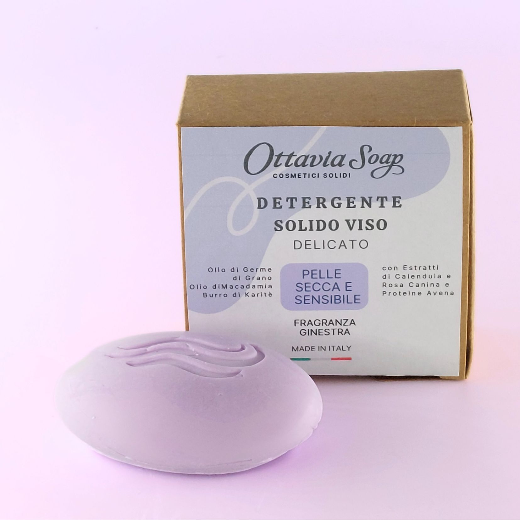 Detergente Solido Viso pelle Secca o delicata In primo piano un panetto di detergente con forma ovale e colore lavanda. In secondo piano la scatola del prodotto con il nome e gli ingredienti in evidenza