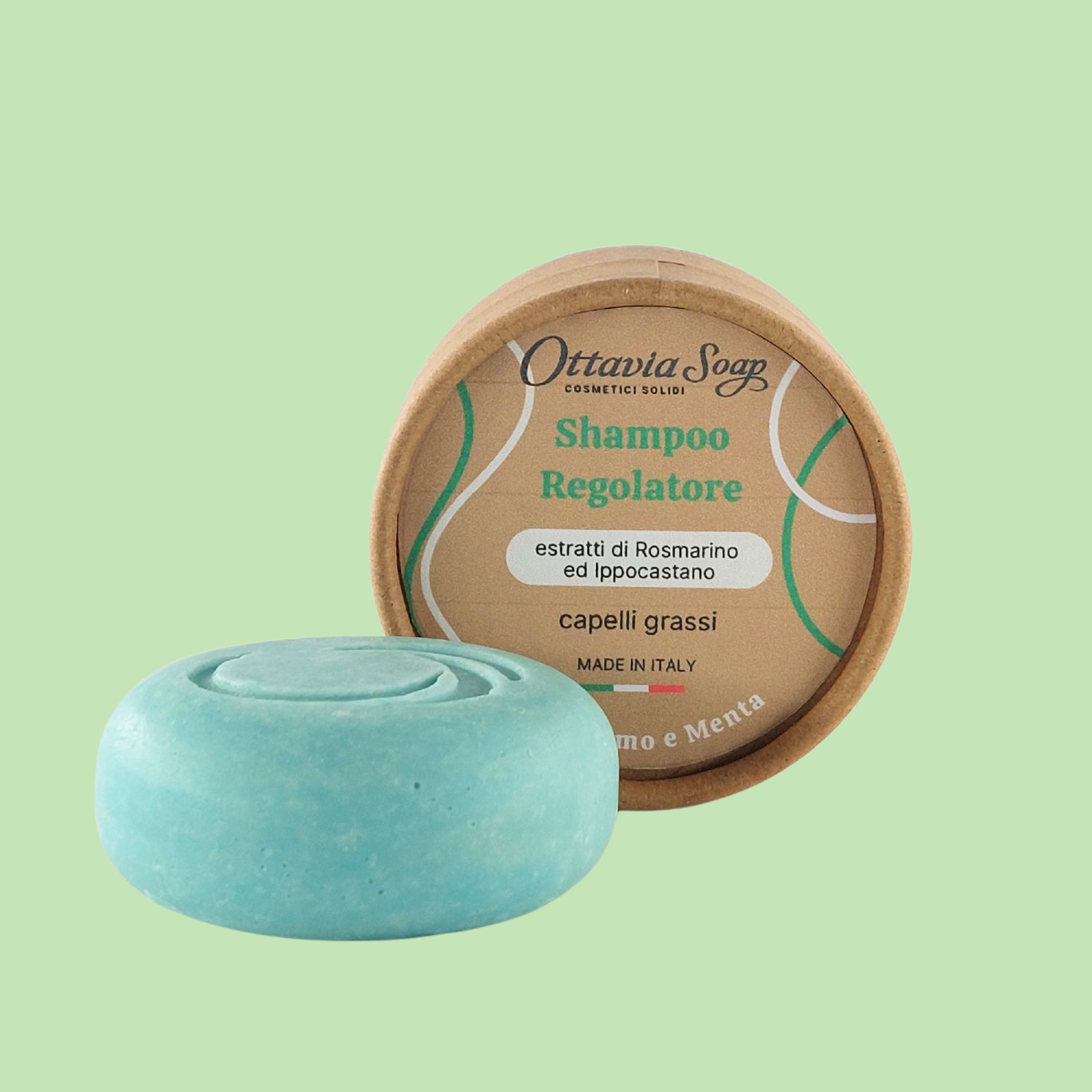 Shampoo solido capelli grassi In primo piano un panetto tondo color verde. Sullo sfondo una scatolina tonda in cartoncino marrone con etichetta dettaglio prodotto